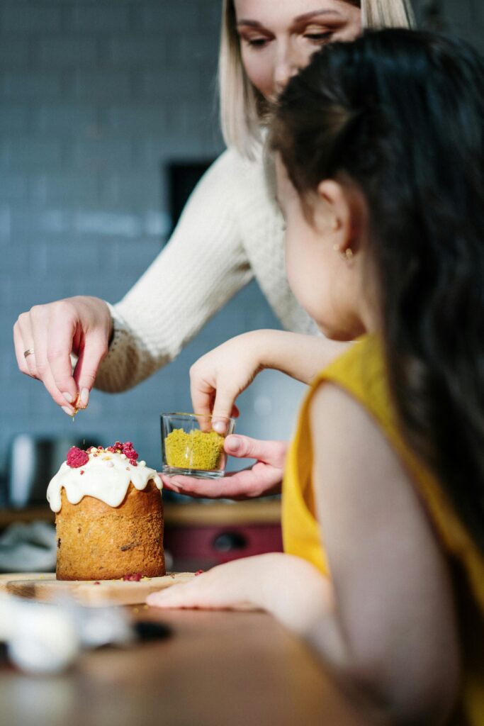 A lovely moment of mother and daughter bonding while decorating an Easter cake in a cozy kitchen.